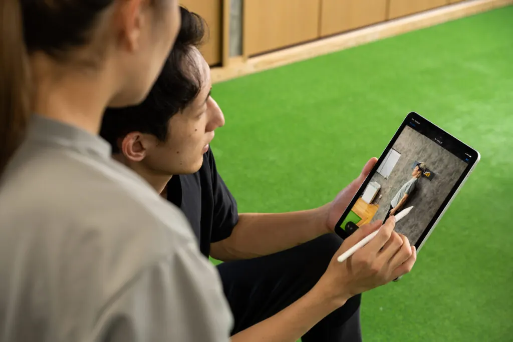 タブレットで姿勢を分析しながら説明するトレーナー