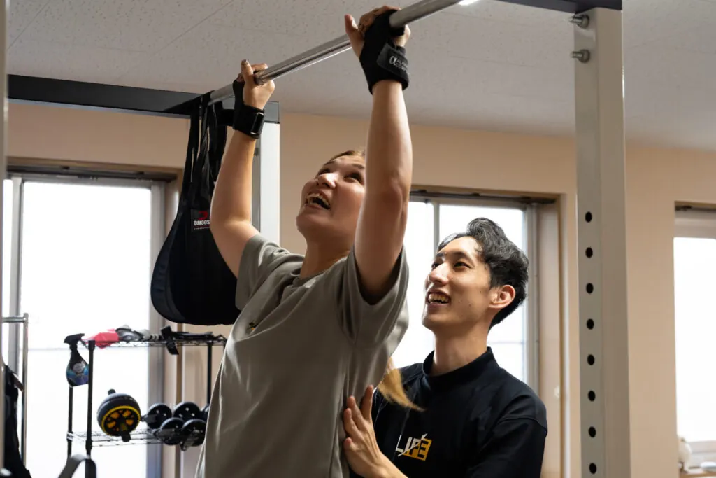 トレーナーのサポートで懸垂トレーニングをするお客様