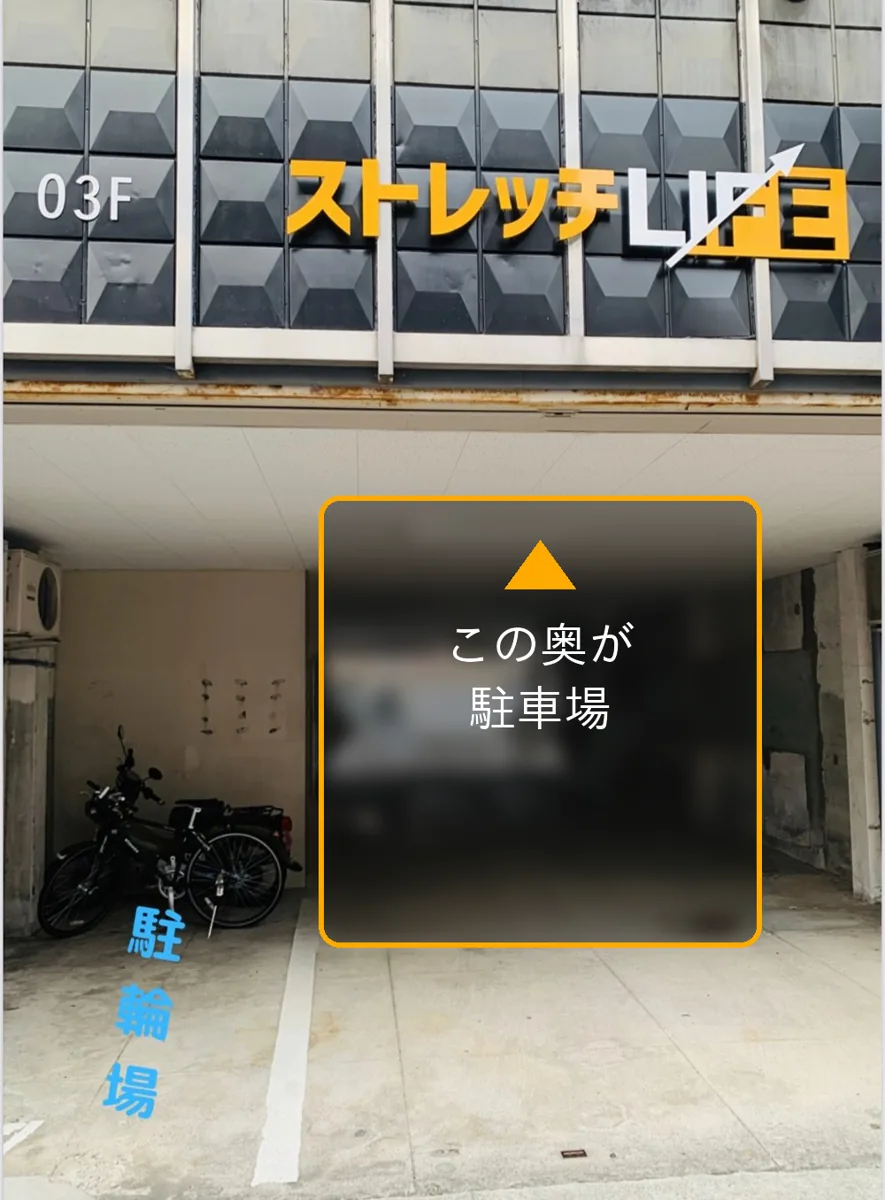 ストレッチLIFEが入る建物の正面。看板の下を入った建物の奥が駐車場、左手前が駐輪場