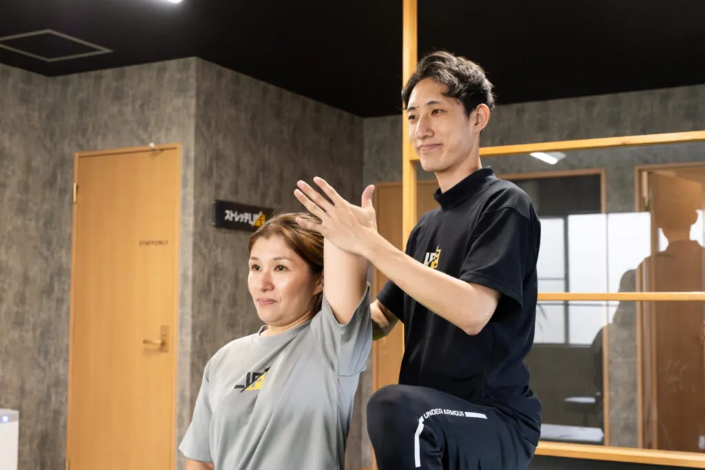 トレーナーが肩の動きを確認しながら指導している様子